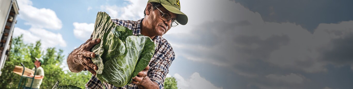 Mož s čelado na delovišču z opremo John Deere v bližini