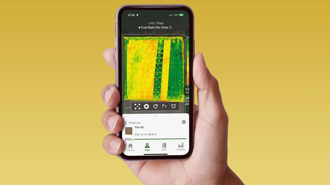 Ročno držanje pametnega telefona, ki prikazuje Operativno središče John Deere s podatki o hitrosti goriva.