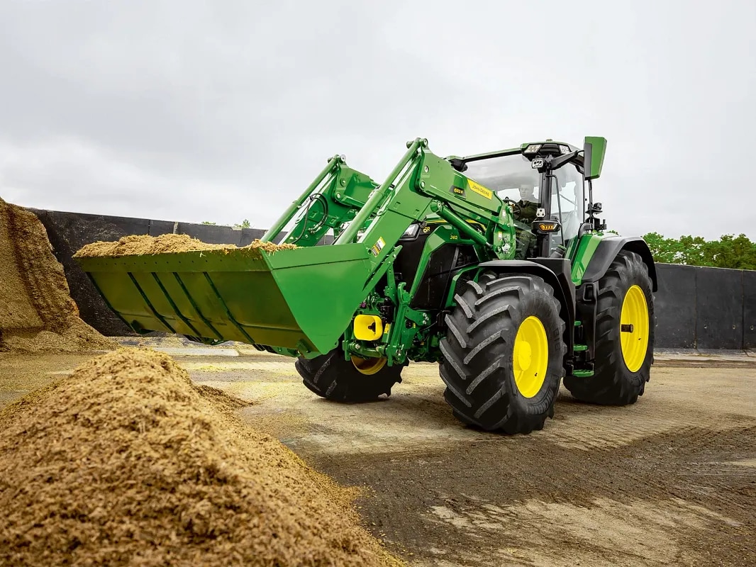 Žlica sprednjega nakladalnika na traktorju John Deere, napolnjena s silažo med natovarjanjem.