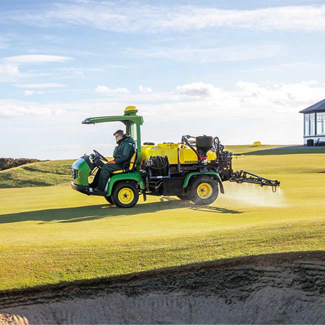 Vzdrževalec zelenic dela na travnatem območju s škropilnikom John Deere