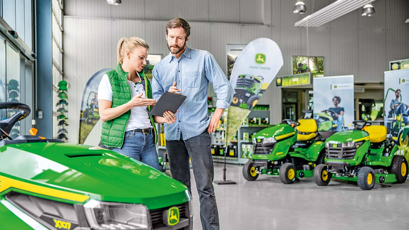 Prodajalec John Deere svetuje stranki pri nakupu kosilnice John Deere.