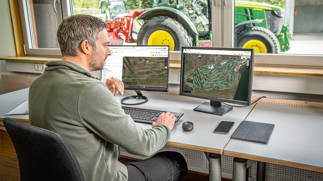 Vodja vzdrževanja zelenic gleda zemljevide igrišča za golf na svojem računalniku.
