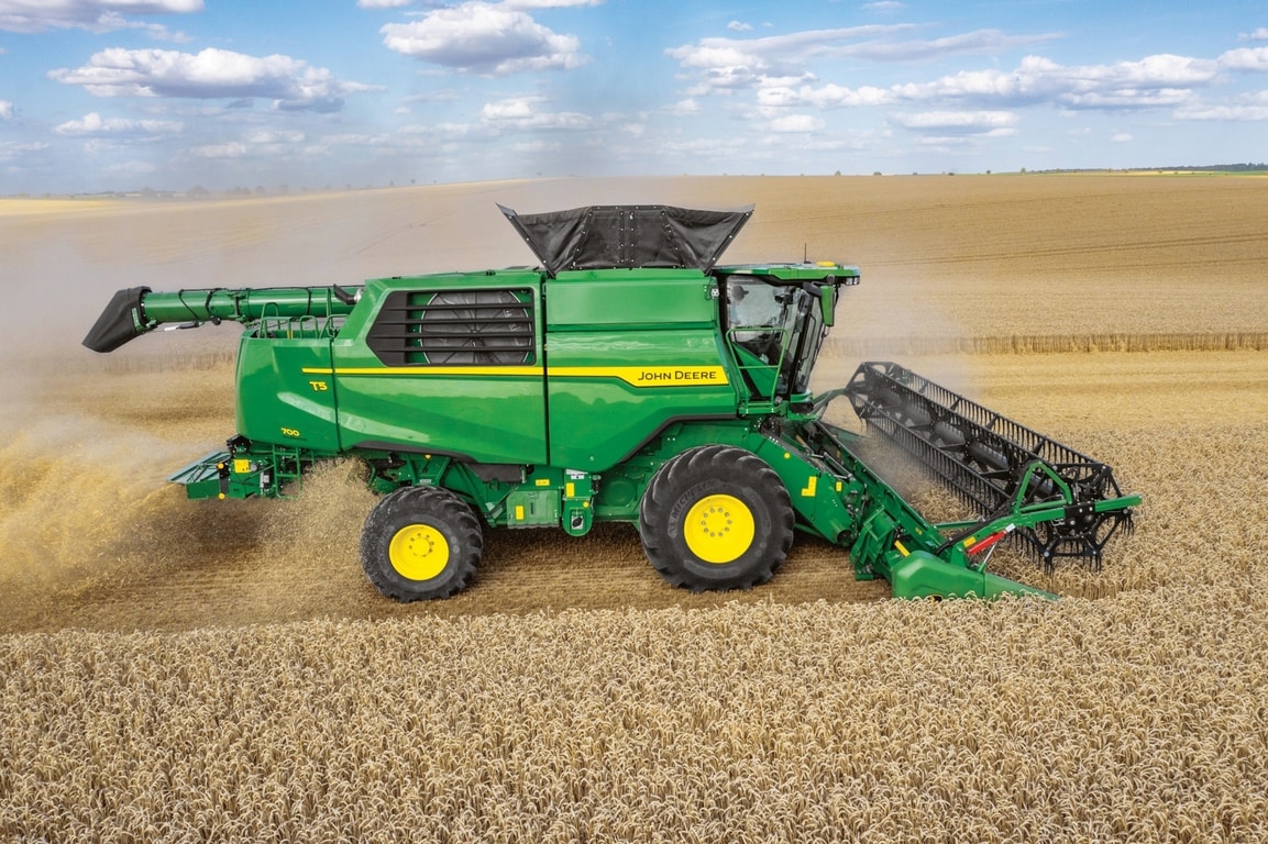 Stranski pogled na kombajn John Deere s hederjem za žetev pšenice na velikem kmetijskem polju
