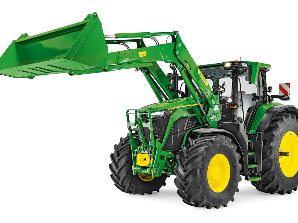 Traktor John Deere s spuščenim sprednjim nakladalnikom in pritrjeno nakladalno žlico, prikazan na belem ozadju.