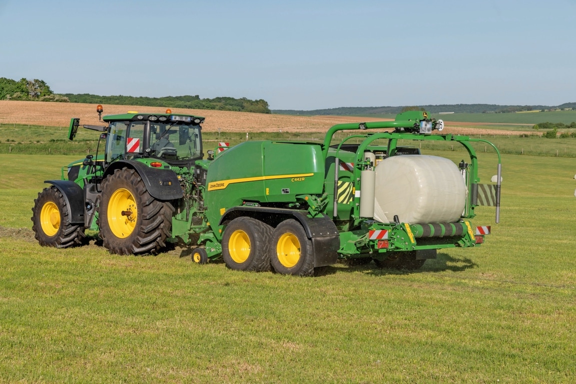 Traktor John Deere 6R 185 vleče balirko za ovijanje John Deere C442R za izdelavo bal za bale silaže visoke gostote